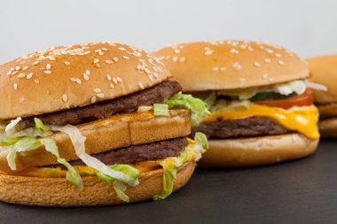 Üç farklı türü ve siyah plakalı ve beyaz arka plan üzerinde lezzetli çizburger boyutunu