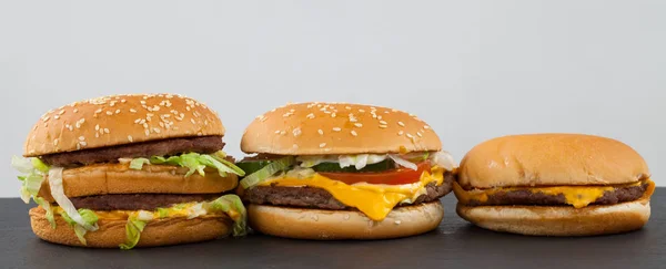 Trzy Różne Rodzaju Wielkości Pyszne Cheeseburgery Talerzu Czarne Białe Tło — Zdjęcie stockowe