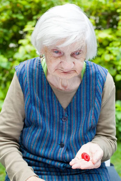 Foto Einer Seniorin Die Mit Himbeere Der Hand Garten Sitzt — Stockfoto