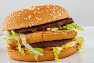 Sığır eti, çedar, marul susam çörek içinde lezzetli bir çizburger resmini kapatın