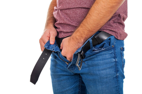 Close up picture of young man with unzipped jeans and  holding his genitals
