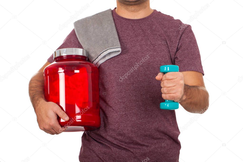 Close up picture of a young man holding a dumbbell and a shake