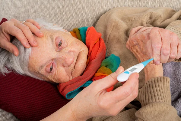 ソファ 介護手手 季節性インフルエンザで休んで病気の高齢者女性の写真を閉じる — ストック写真