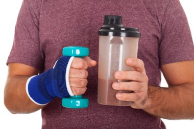 Genç adam bir protein shake ve bir dumbbell tutarak