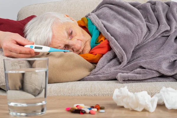 Άρρωστη ηλικιωμένη γυναίκα στον καναπέ — Φωτογραφία Αρχείου