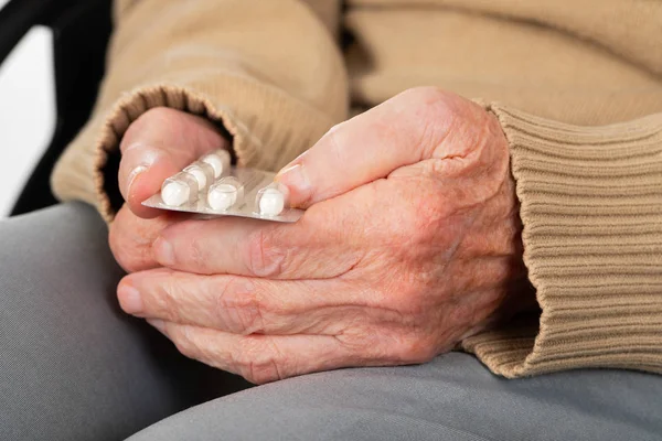 Mãos idosas segurando pílulas — Fotografia de Stock