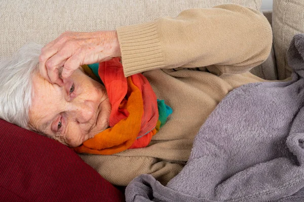 Gammal dam liggande på soffan — Stockfoto