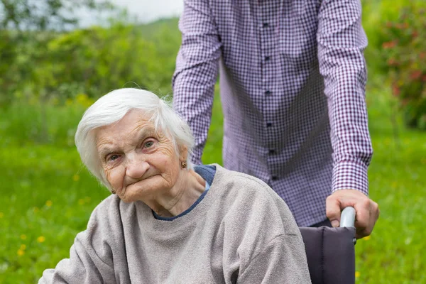 Idős hölgy demenciában, tolószékben és gondozója — Stock Fotó