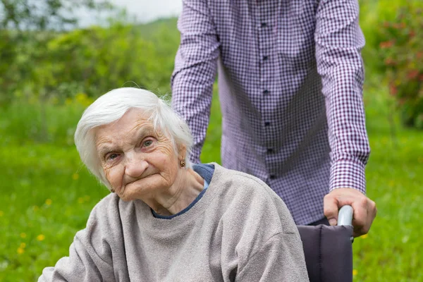 Vieille dame avec démence dans un fauteuil roulant et soignant — Photo