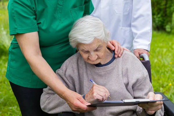 의료 지원이 있는 휠체어를 탄 노인 여성 — 스톡 사진