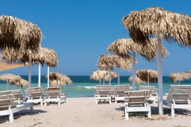 Plajda renkli şezlonglar ve şemsiyeler