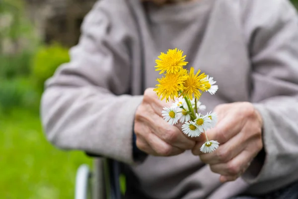 Elderly shaking hands holding flowers — Stock Photo, Image