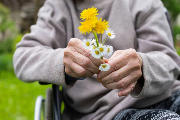 Elderly shaking hands holding flowers