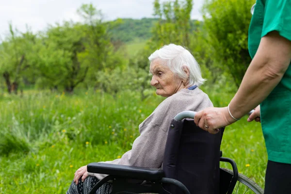 Leeftijd vrouw in een rolstoel met medische hulp — Stockfoto