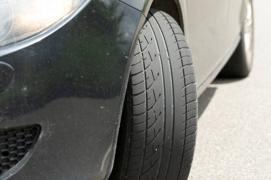 Siyah arabanın yepyeni lastiğinin bir yaz günü yoldaki resmi.