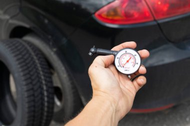 Siyah arabanın yepyeni lastiğinin bir yaz günü yoldaki resmi.