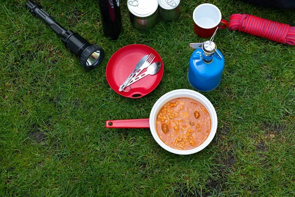 Picture of camping tools on the grass - backpack, tent, gas tank, cans, compass, etc - ready to go in the woods