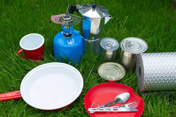 Picture of camping tools on the grass - backpack, tent, gas tank, cans, compass, etc - ready to go in the woods