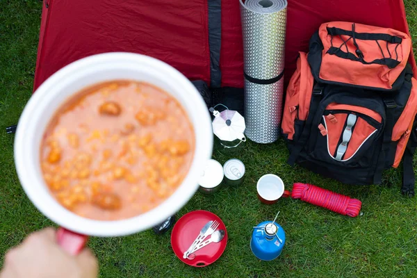 Picture of camping tools on the grass - backpack, tent, gas tank, cans, compass, etc - ready to go in the woods