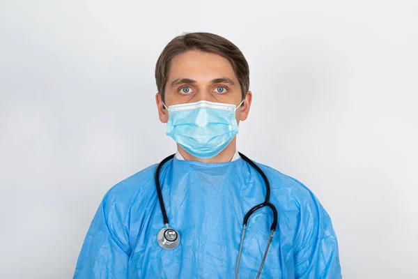 Joven Médico Varón Con Máscara Quirúrgica Uniformes Protectores Sobre Fondo —  Fotos de Stock