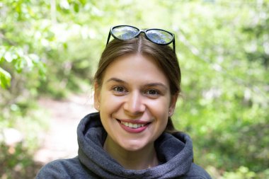 Güneş gözlüğü takan ve kameraya satış yapan güzel genç bir kadın.