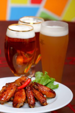 bira renkli bir arka plan üzerinde beyaz tabak keskin tavuk kanadı üzerinde