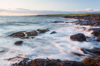 Deniz kıyısı üzerinde gün batımı sırasında uzun pozlama üzerinde dalga deniz