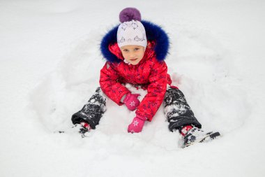 bir kız kışın karda oynuyor