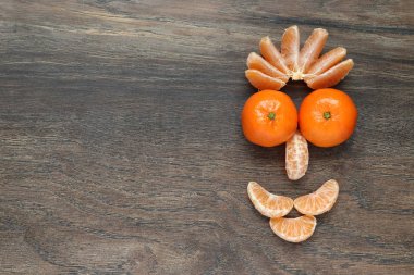 arka plan kopya alanı ile ahşap bir tahta bir gülümseme ile stilize bir yüz şeklinde soyulmuş ve soyulmamış mandalina bileşimi