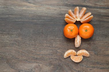 arka plan kopya alanı ile ahşap bir tahta bir gülümseme ile stilize bir yüz şeklinde soyulmuş ve soyulmamış mandalina bileşimi