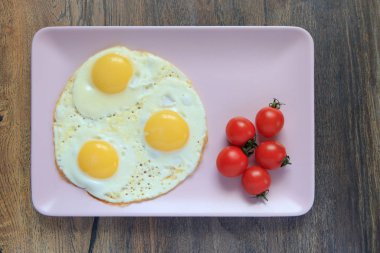 sahanda yumurta, domates ahşap tahta arka plan üzerinde bir kare plaka üzerinde