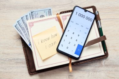 bize dolar ile Organizatör ve açık hesap makinesi numaraları 1 000 000 ve yapışkan notu ile levha ile bir yazıt ben nasıl biliyorum, ben bir masa arka plan üzerinde