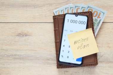 bize dolar ve sayılarla 1 000 000 açık hesap makinesi ve yapışkan not sayfası ile bir yazıt Busines Plan ve arka plan üzerinde kopya alanı ile bir masa ile Organizatör