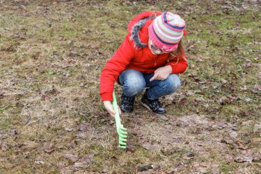 Kız parkta düşmüş yaprakları ilkbaharda temizler.