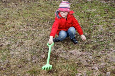 Kız parkta düşmüş yaprakları ilkbaharda temizler.