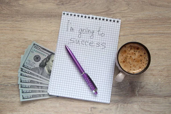 notepad with a  pen, cup of coffee  and US dollars with the inscription I\'m going to success