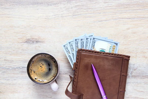 organizer with us dollars and a cup of coffee and a pen on the background of a desk with copy space