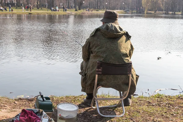 man sitting on a folding chair fishing in a lake