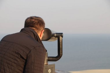 adam denizde gün batımı sırasında dürbün manzara inceler