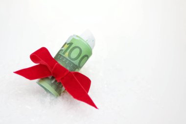 bir Noel hediyesi, gibi 100 euro banknot bir kalın hediye rulo arka planda karda bir kırmızı yay ile bağlı