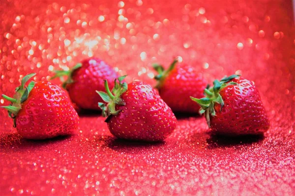 Juicy berries of red strawberry, against a red shiny background, selective focus — Stock Photo, Image