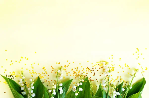 Λευκά άνθη ενός κρίνο της κοιλάδας σε ένα θερμό κίτρινο φόντο. — Φωτογραφία Αρχείου