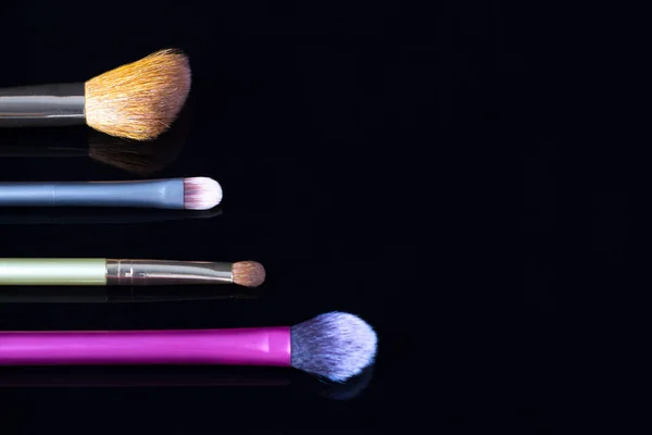 Pinceles de maquillaje sobre fondo negro. Cosméticos, moda, belleza, glamour. Accesorios para maquillador . — Foto de Stock