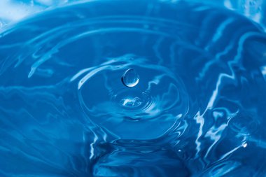 Mavi yüzeye su damlar. Su dalgalanması arka plan. Bir damla sudan su sıçratıyor. Mavi arka plandaki yağmur damlaları. Suyun dokusu. Aqua, turkuaz, makro