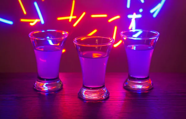 Trois verres à la fête. Trois verres avec des cocktails au bar. Liqueur, vodka, fraîche. Brillant sur un fond coloré. Boîte de nuit, après la fête . — Photo