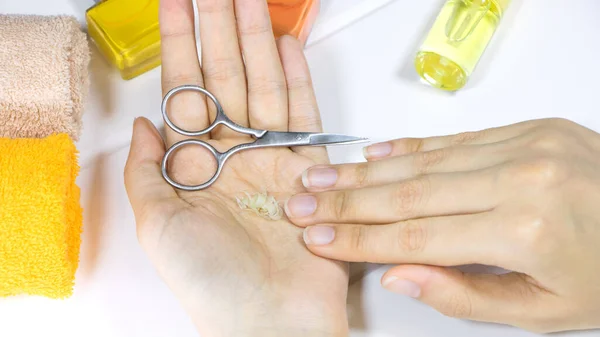 Manicure. A woman holds a cut-off nails in her hand. Cut your fingernails with small nail scissors. Trim your nails. Young woman taking care of her nails. Hygiene, clipping, cutter, self, procedure.