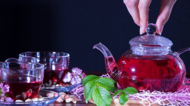 Kırmızı çay, ambar, karkade, Rooibos. Bir kadın çay yapar. Tören, öğleden sonra çayı, kahvaltı. Çay zamanı, Carcade. Doğulu, samimi, geleneksel, Japon, yapraklı, hygge, sonbahar, saat 5 yönünde, yapraklar, kupa, dök