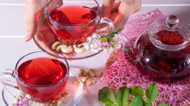 Çay ikram etmek için. Biraz çay al. Bir kadın elinde bir kupa çay tutuyor. Kırmızı çay, ambar, karkade, Rooibos. Tören, öğleden sonra çayı, kahvaltı. Çay zamanı, Carcade. Doğulu, rahat, gelenek, Japon, yapraklı, hygge, 