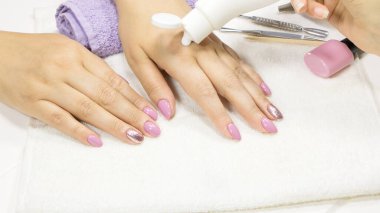Manikürcü, müşterinin eline nemlendirici sürüyor. SPA manikür, prosedür, nemlendirici. El losyonu, krem. Cilt bakımı. Güzellik salonu. Manikür konsepti. Güzel tırnaklar. Yumuşak ten. Kozmetik kremi