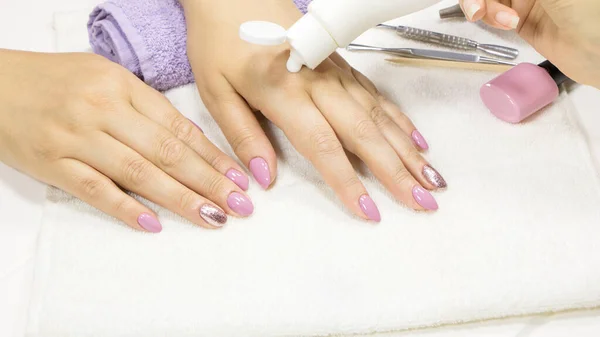 The manicurist applies a moisturizer to the client\'s hand. SPA manicure, procedure, moisturizing. Hand lotion, cream. Skin care. Beauty salon. Manicure concept. Beauty nails. Soft skin. Cosmetic cream